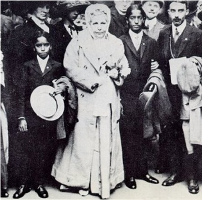 Die Theosophin Annie Besant im hellen Mantel, rechts neben ihr Krishnamurti, links neben ihr Krishnamurtis jüngerer Bruder Nitya und hinter diesem George Arundale im Jahr 1911 in England 6